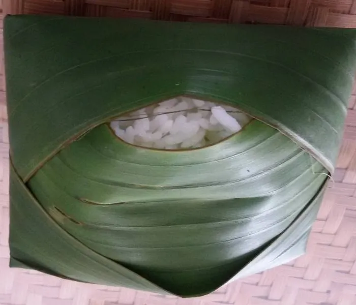 Banana leaf rice with white rice and small portions of curry, dhal, rasam, and papadum arranged on a green leaf