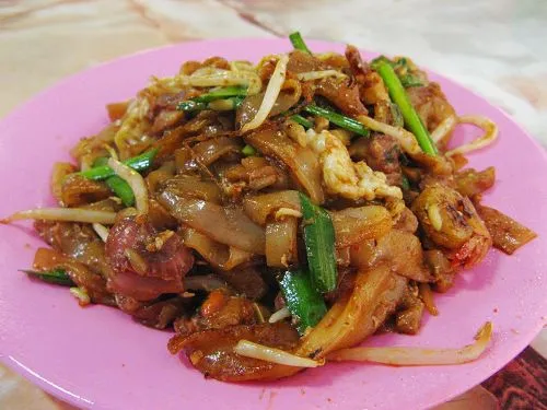 Char kway teow in a dark wok-charred bowl with prawns and bean sprouts