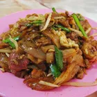 Char kway teow in a dark wok-charred bowl with prawns and bean sprouts