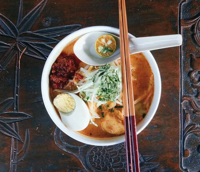 Curry laksa in a bowl with coconut broth, rice noodles, prawns, and tofu puffs