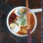 Curry laksa in a bowl with coconut broth, rice noodles, prawns, and tofu puffs