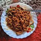 Mee goreng mamak in a wok-fried heap of yellow noodles, egg, and vegetables with a dark sauce