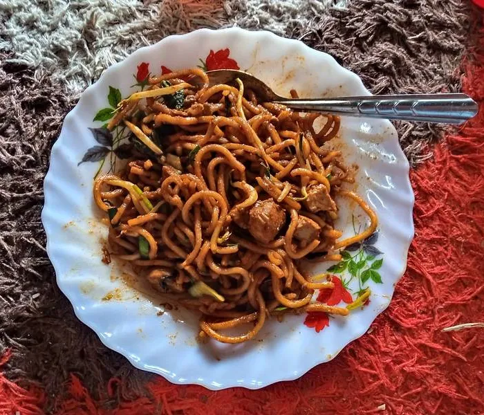 Mee goreng mamak in a wok-fried heap of yellow noodles, egg, and vegetables with a dark sauce