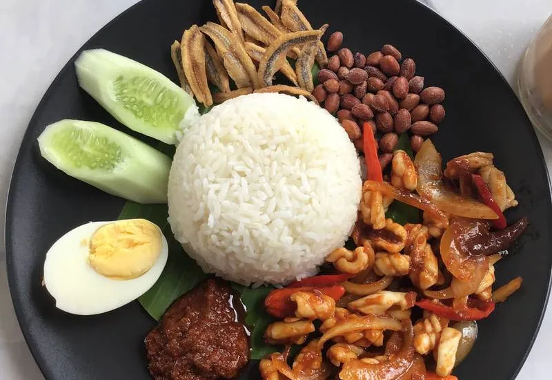 Nasi lemak on a banana leaf with sambal, anchovies, and egg