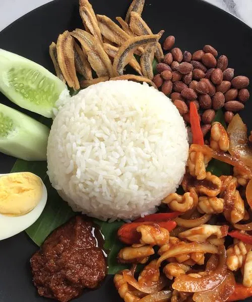Nasi lemak on a banana leaf with sambal, anchovies, and egg