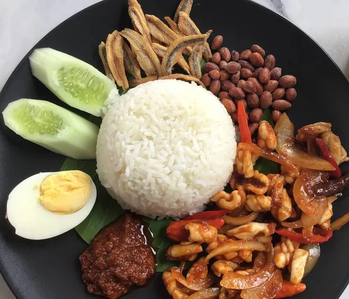 Nasi lemak on a banana leaf with sambal, anchovies, and egg
