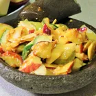 Rojak salad with sliced fruits, cucumber, and tofu in a dark thick sauce topped with crushed peanuts