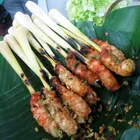 Chicken satay skewers on a charcoal grill, with peanut sauce and cucumber