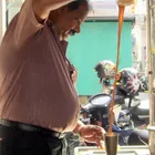 Teh tarik being poured from height between two metal cups, creating a thick froth